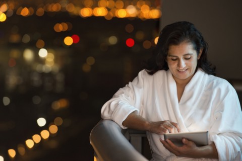 Hispanic woman using digital tablet on hotel balcony