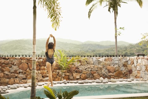 Hispanic woman stretching by swimming pool