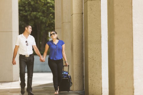 Hispanic couple holding hands under columns