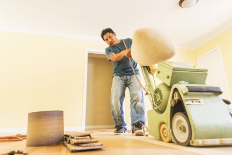 Hispanic man refinishing floors in new house