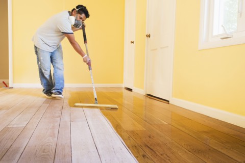 Hispanic man refinishing floors in new house
