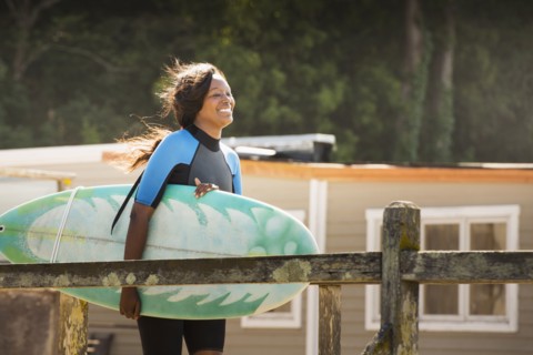 African American woman carrying surfboard outdoors