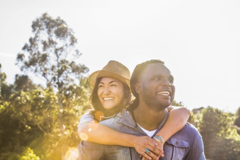 Man carrying girlfriend piggyback outdoors