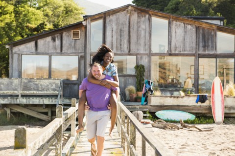 Man carrying girlfriend piggyback on wooden deck