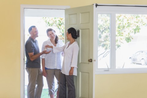 Real estate agent giving couple keys to new home