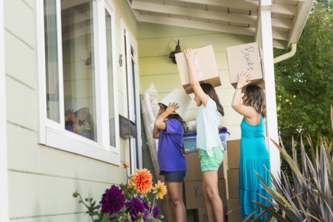 Children carrying cardboard boxes into house