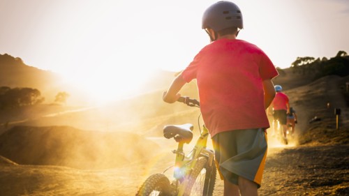Mixed race boy riding dirt bike on track