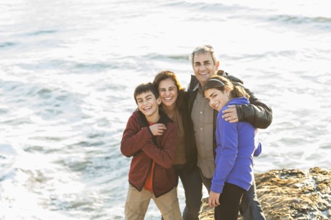 Family hugging near ocean waves