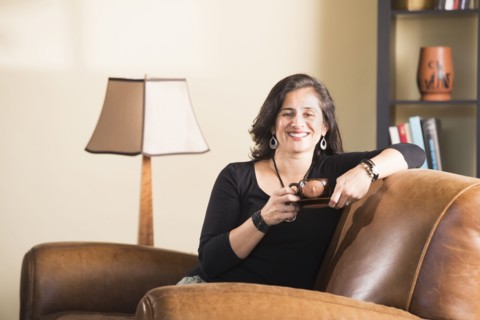 Hispanic woman sitting in armchair drinking coffee