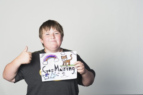 Boy holding sign gesturing thumbs-up