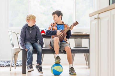 Boys siting on bench with ukulele and soccer ball