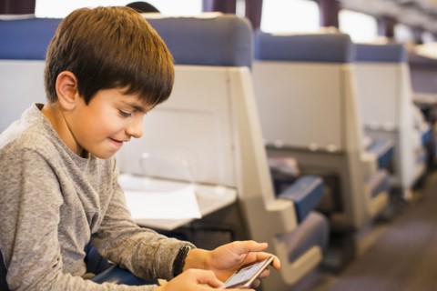 Mixed Race boy using cell phone on train