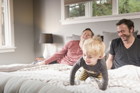 Caucasian fathers playing on bed with son