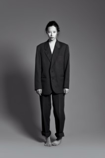 Barefoot Asian woman wearing large suit