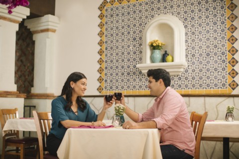 Hispanic couple toasting with wine in restaurant