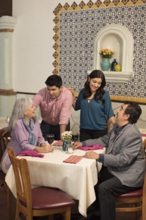 Younger couple greeting older couple in restaurant