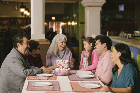 Family celebrating birthday of older woman in restaurant