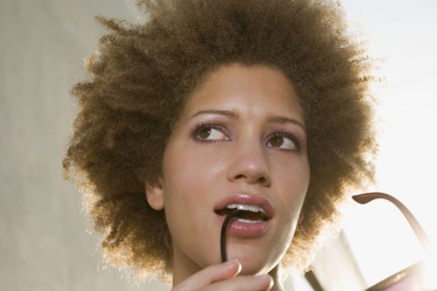 Mixed race woman biting on sunglasses