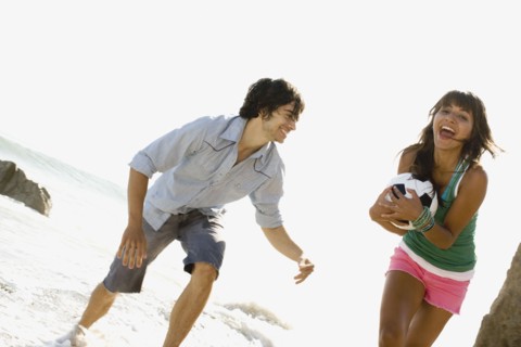 Couple playing with soccer ball on beach