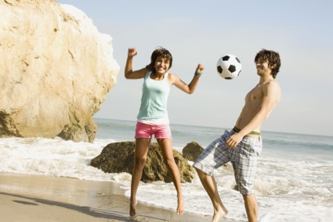 Couple playing with soccer ball on beach