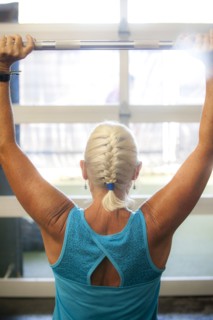 Older woman lifting barbell in gymnasium