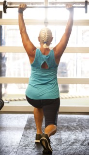 Older woman lifting barbell in gymnasium