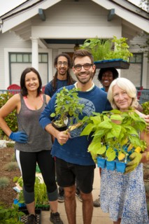Portrait of neighbors holding plants near house