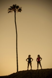 Mixed Race mother and daughter standing near palm tree
