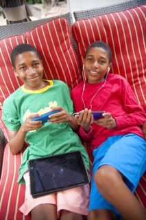 Portrait of Black twin boys using cell phones outdoors