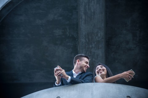 Low angle view of couple on balcony texting on cell phones
