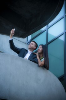 Low angle view of couple on balcony posing for cell phone selfie