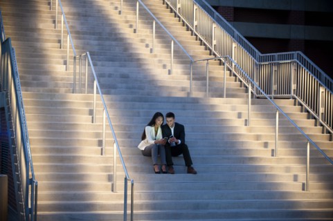 Couple sitting on staircase texting on cell phones