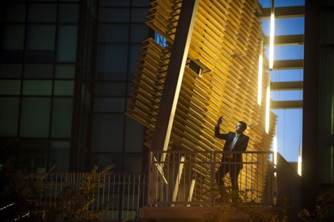 Businessman on balcony posing for cell phone selfie at night