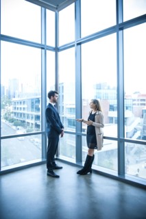 Businessman and businesswoman talking near window