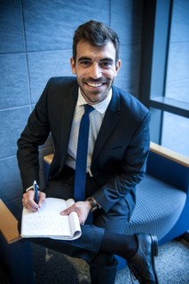 Smiling Hispanic businessman writing on notepad in office lounge