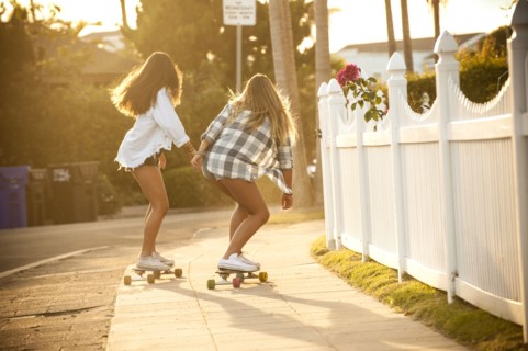 Teenage girls skateboarding on sidewalk