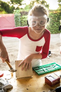 Girl hammering nails into birdhouse