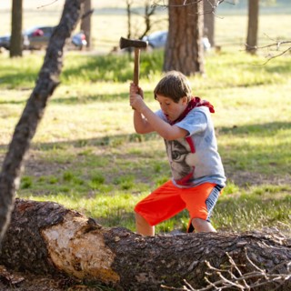 Caucasian boy chopping log with axe