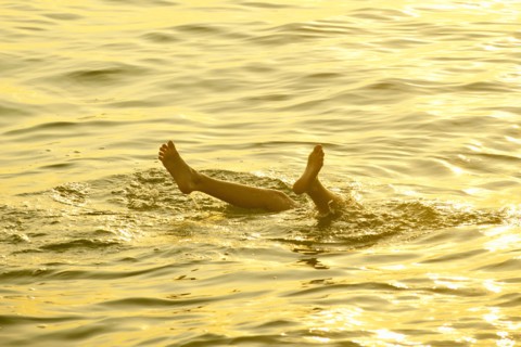 Feet of Caucasian boy sticking out of water