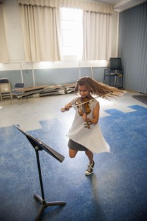 Caucasian girl practicing violin and dancing