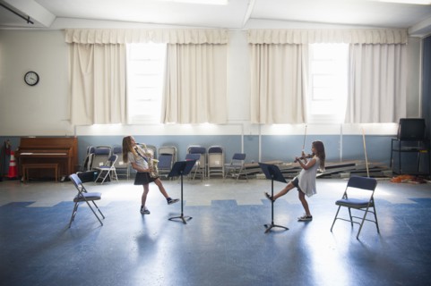 Caucasian girls practicing violins and dancing