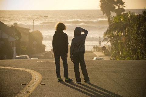Boys standing in street admiring ocean waves