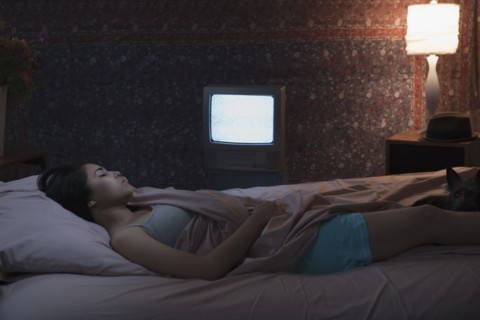 Hispanic woman sleeping with television on