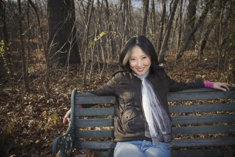 Smiling Asian woman sitting on park bench