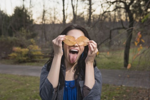 Playful Caucasian woman with leaves covering her eyes