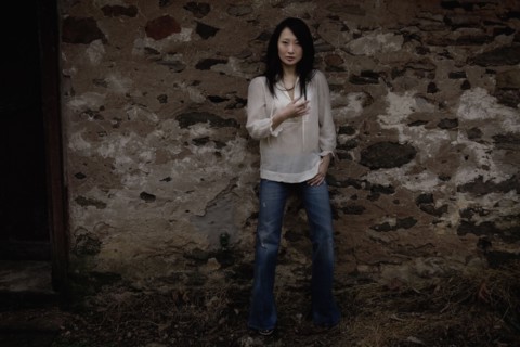 Serious Asian woman leaning against wall