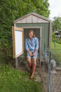 Older Caucasian woman smiling at chicken coop