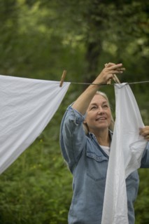 Older Caucasian woman hanging laundry on clothesline