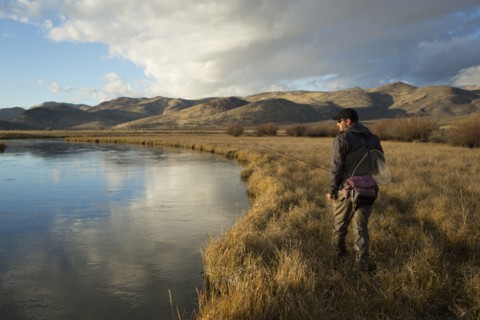 Man carrying fishing supplies near river