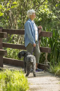 Older Caucasian woman walking dog in park